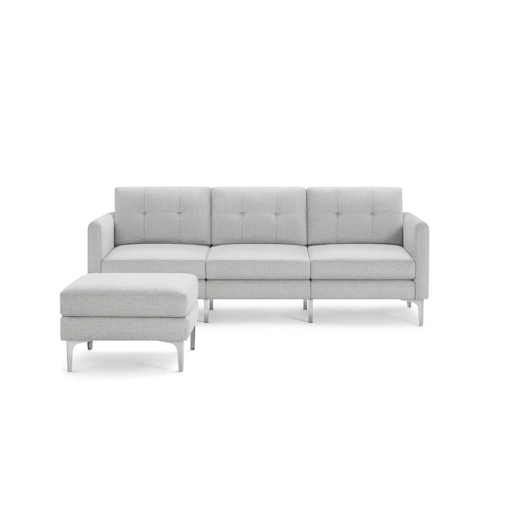Light gray sectional sofa with tufted back cushions and matching ottoman, supported by sleek silver legs.
