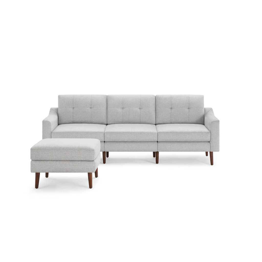 Light gray mid-century modern sectional sofa with tufted cushions and matching ottoman, supported by wooden legs.