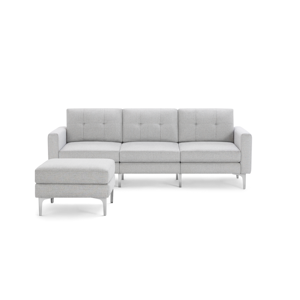 Light gray modern three-seat sofa with tufted back cushions and matching ottoman, supported by sleek metal legs.