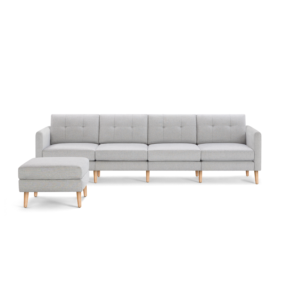 Light gray modern sectional sofa with tufted cushions, wooden legs, and a matching ottoman on the left side.