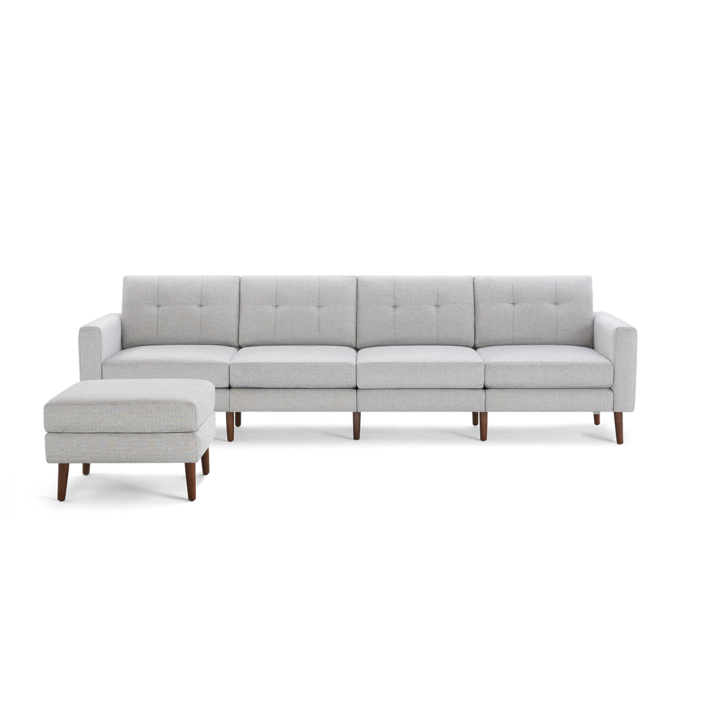 Light gray modern sectional sofa with four seat cushions, tufted backrests, wooden legs, and matching ottoman.