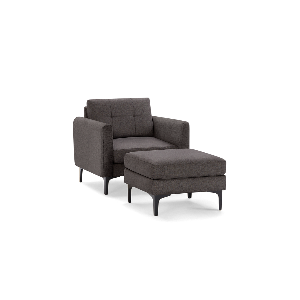 Modern dark gray upholstered armchair with matching cushioned ottoman, featuring slim black legs and tufted backrest.