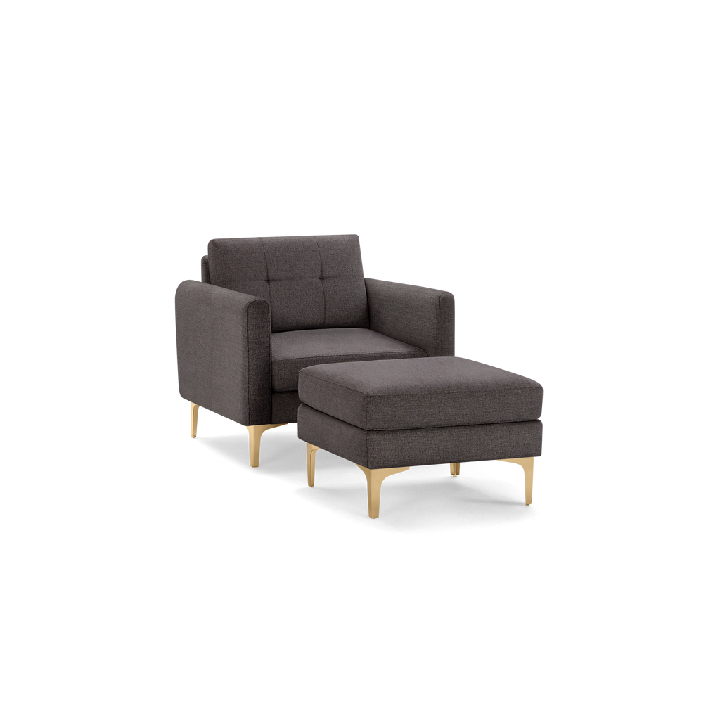 Dark gray upholstered armchair with matching ottoman, both featuring tufted cushions and gold metal legs.