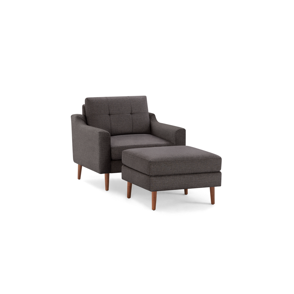 Dark gray upholstered armchair with matching ottoman, featuring wooden tapered legs and tufted backrest design.
