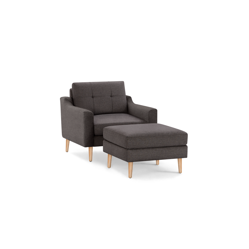 Modern dark gray fabric armchair with plush cushion and matching ottoman, both featuring natural wooden legs.