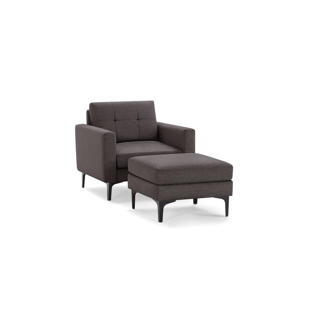 Dark gray upholstered armchair with tufted backrest and matching ottoman, featuring sleek black legs.
