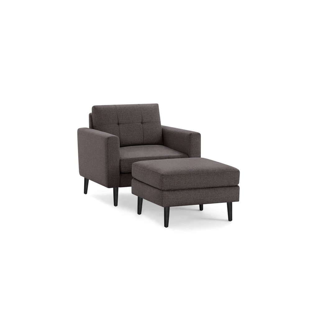 Dark gray upholstered armchair with matching ottoman, featuring wooden legs and tufted backrest, modern design.