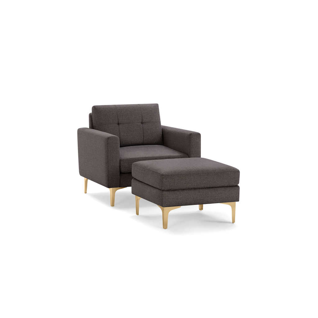 Modern dark gray armchair with tufted backrest and matching cushioned ottoman, featuring light wooden legs.