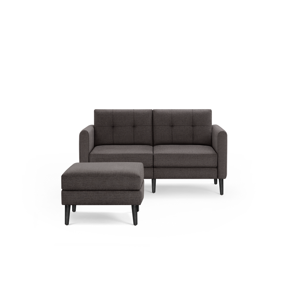 Modern dark gray fabric loveseat with tufted back cushions and matching ottoman, supported by black wooden legs.