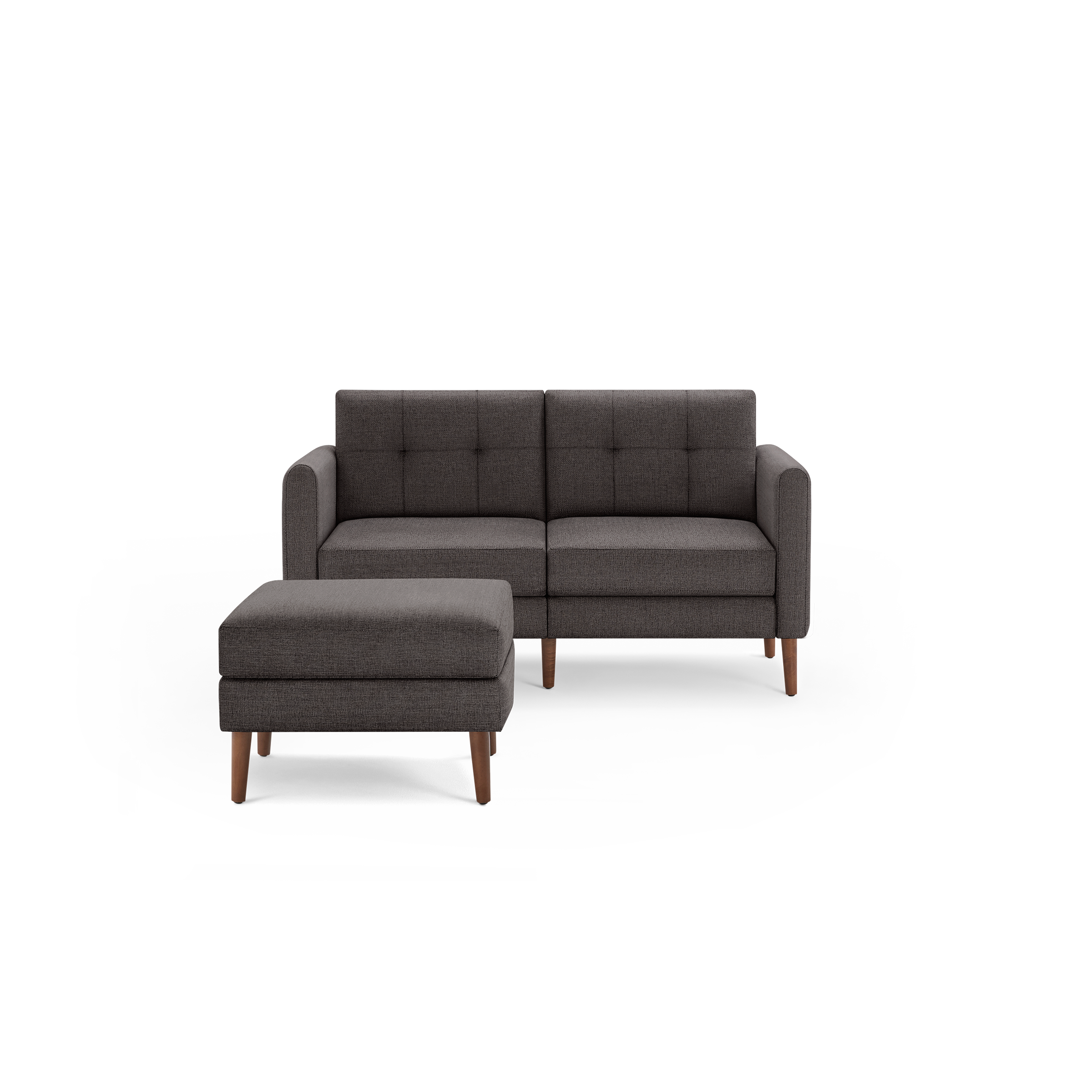 Dark gray upholstered modern sofa with matching ottoman, wooden legs, and tufted back cushions, isolated on white background.