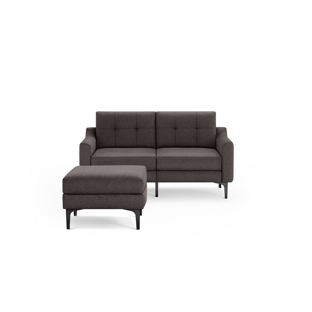Modern dark gray fabric loveseat with tufted backrest and matching cushioned ottoman on black metal legs.