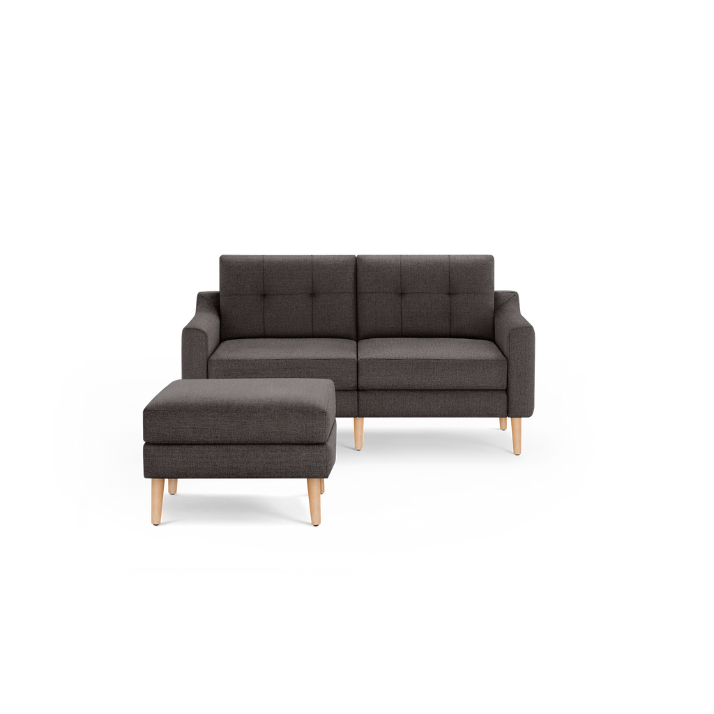 Dark gray fabric loveseat with tufted backrest and matching ottoman, both featuring light wooden legs.