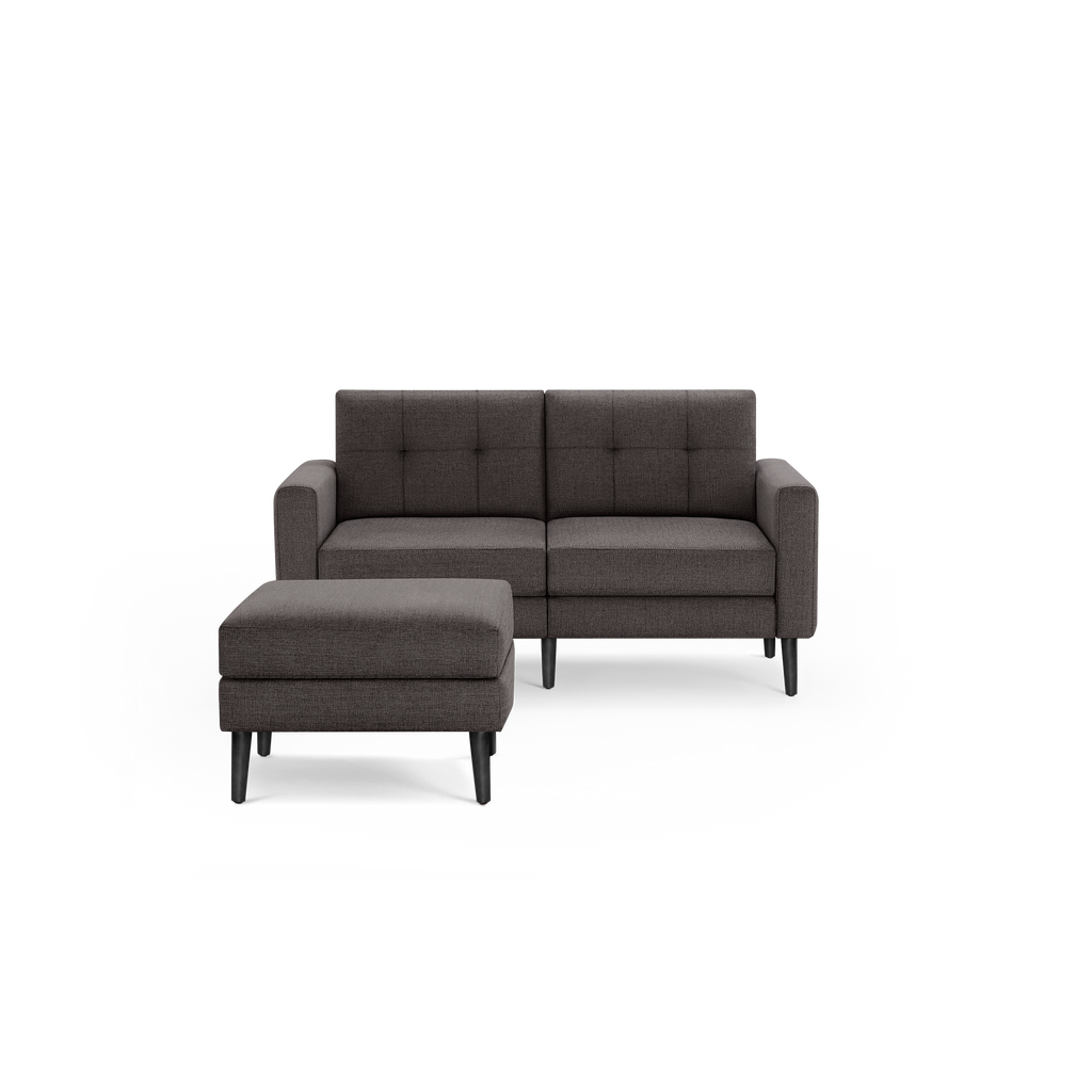 Compact dark gray tufted fabric loveseat with square arms and matching cushioned ottoman, both with black tapered legs.
