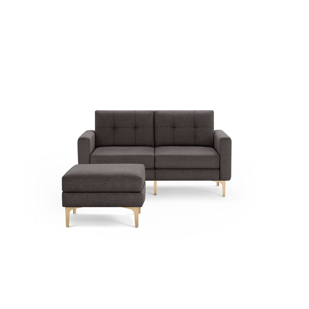 Dark gray upholstered modern loveseat sofa with tufted back cushions and a matching ottoman, both with light wooden angled legs.