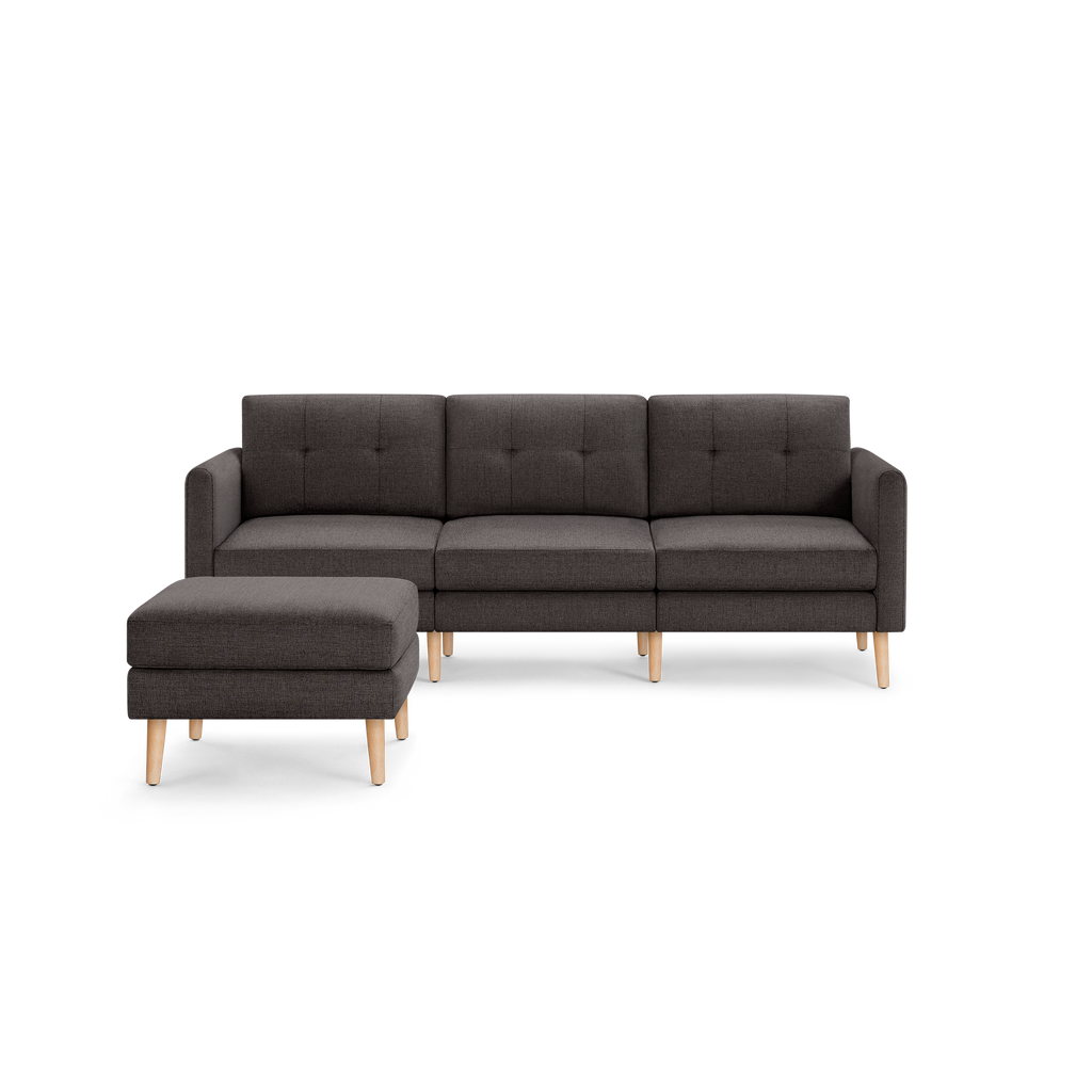 Dark gray L-shaped sectional sofa with tufted cushions and light wooden legs, including a matching ottoman.