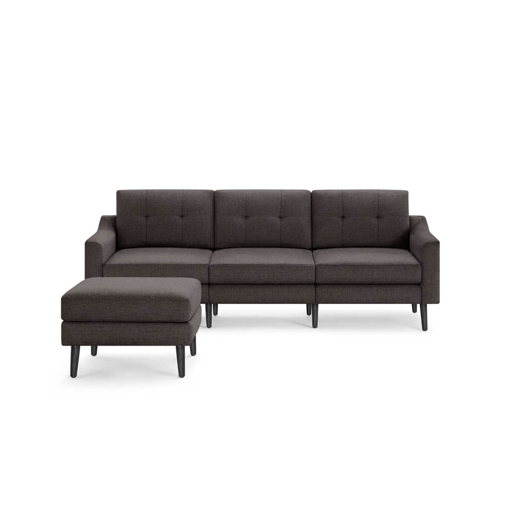 Dark gray three-seater sectional sofa with tufted back cushions and matching ottoman, supported by black wooden legs.