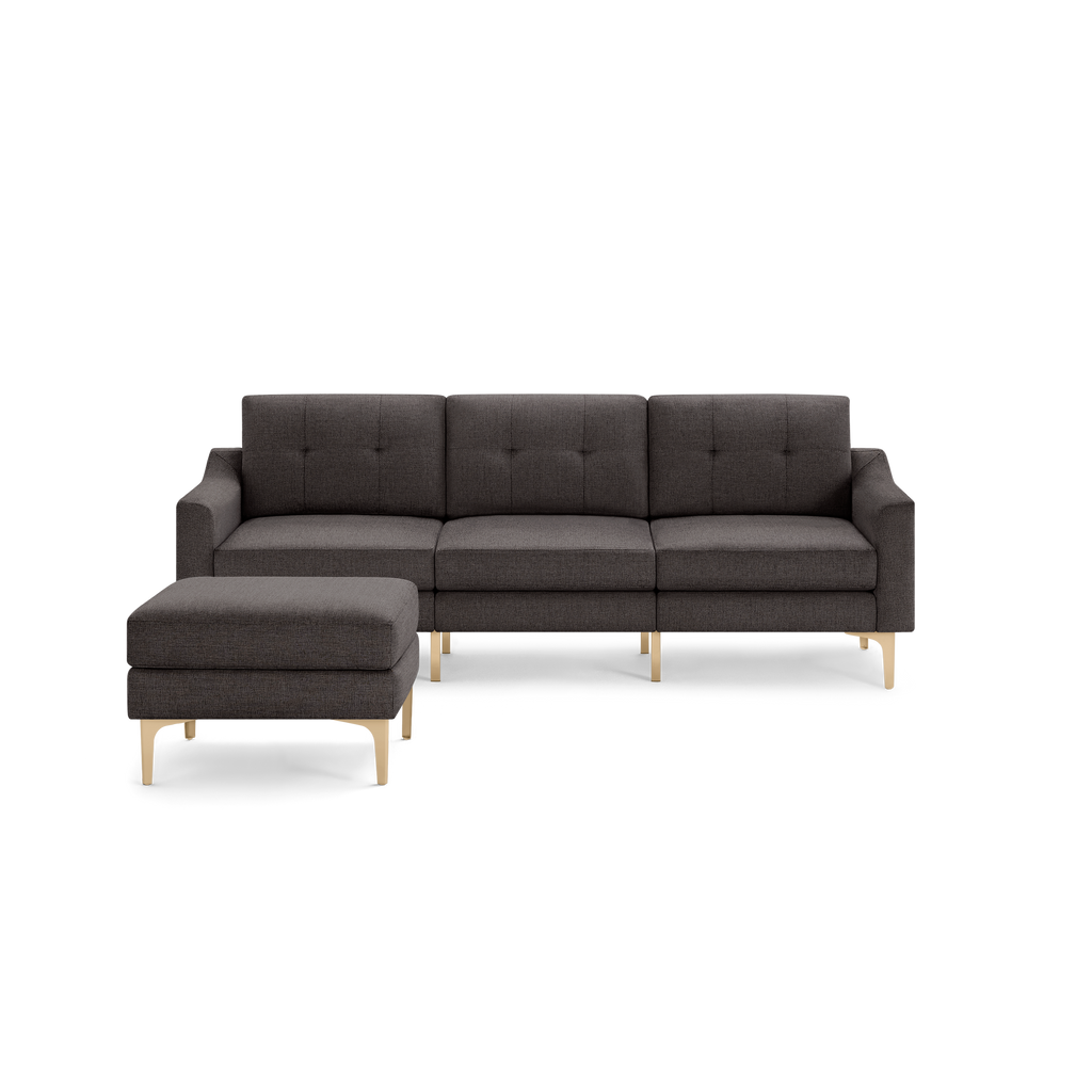 Dark gray fabric sectional sofa with tufted back cushions, clean lines, and light wooden legs, including a matching ottoman.