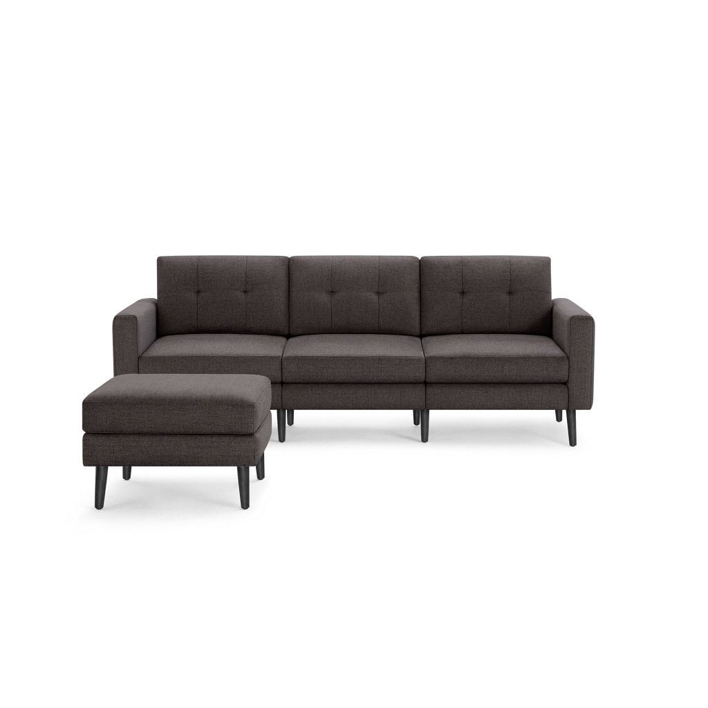 Dark gray three-seater sofa with button-tufted back cushions and matching ottoman, featuring wooden tapered legs.