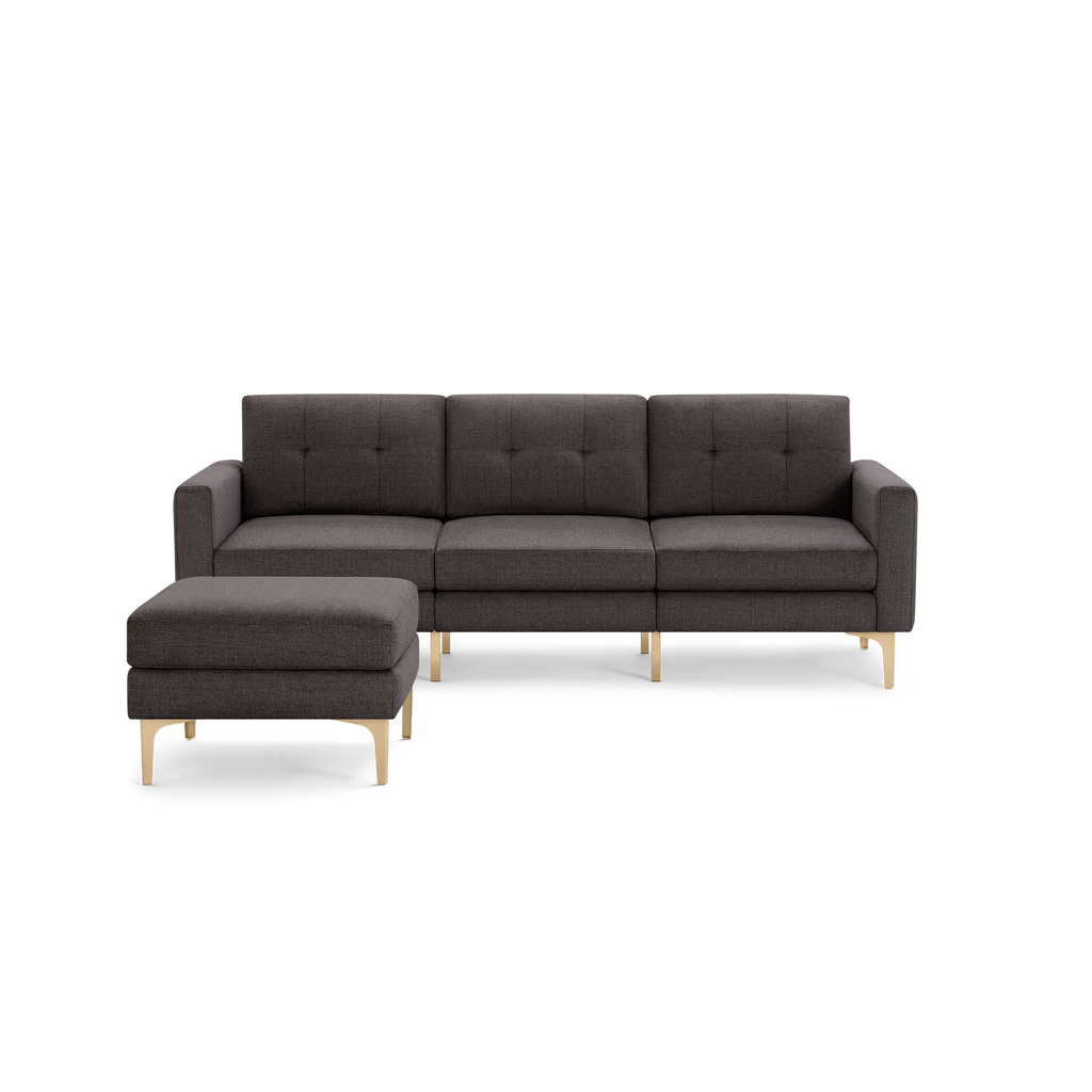 Modern dark gray fabric sectional sofa with tufted back cushions and light wooden legs, paired with a matching ottoman.