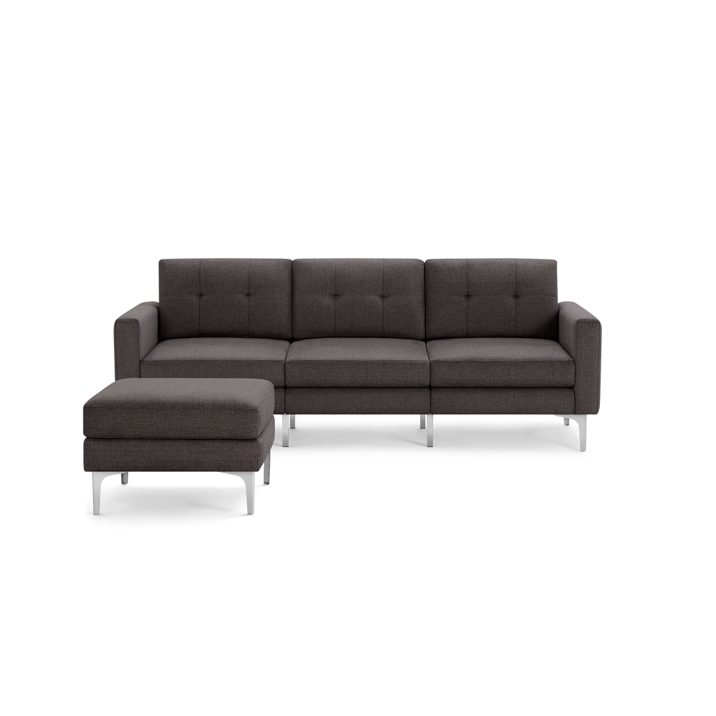 Dark gray fabric sectional sofa with tufted back cushions and a matching ottoman, supported by sleek silver metal legs.