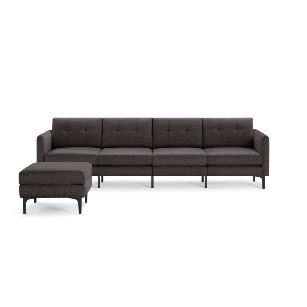 Modern dark gray fabric sectional sofa with tufted backrest, four seats, armrests, and a matching cushioned ottoman on black legs.