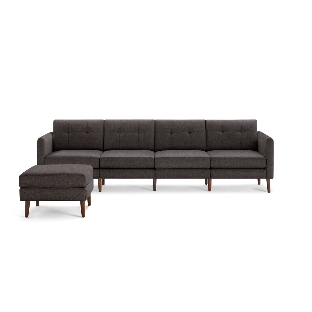 Dark gray modern sectional sofa with tufted back cushions, wooden legs, and matching ottoman on black background.