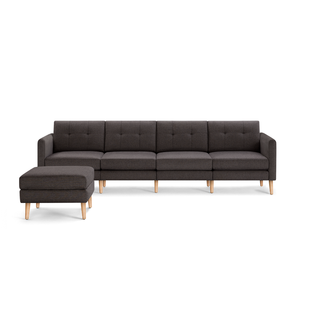 Dark gray modern sectional sofa with tufted back cushions and light wooden legs, accompanied by matching ottoman.