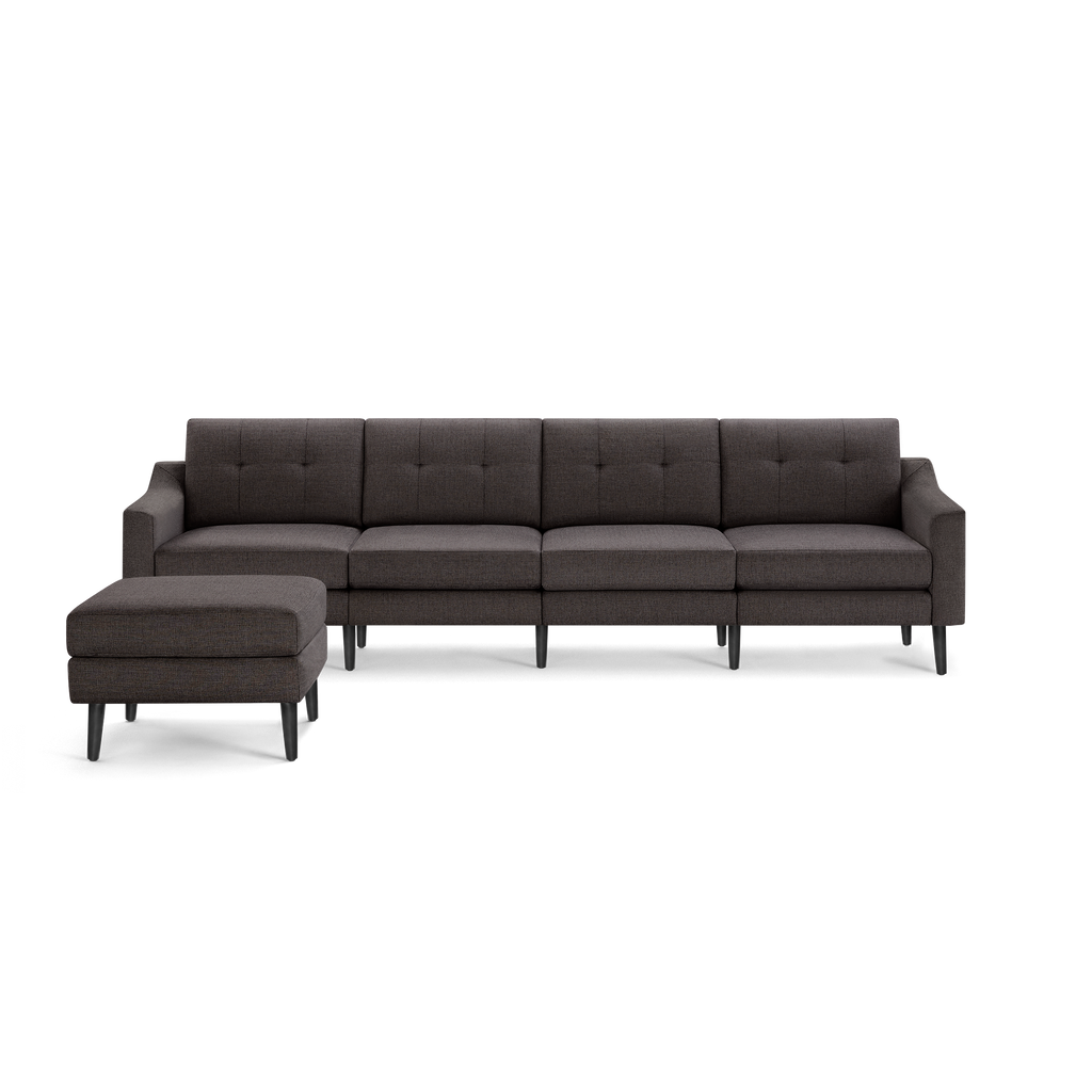Dark gray fabric sectional sofa with tufted back cushions and matching ottoman on black tapered legs, modern design.
