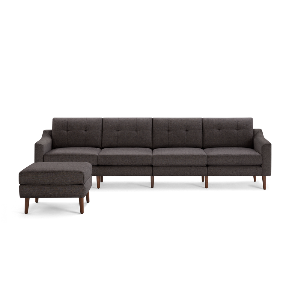 Dark gray fabric sectional sofa with tufted back cushions and wooden legs, paired with matching ottoman.