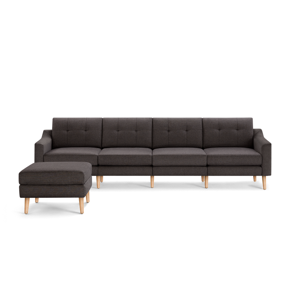 Dark gray fabric sectional sofa with tufted back cushions and light wooden legs, including a matching ottoman.