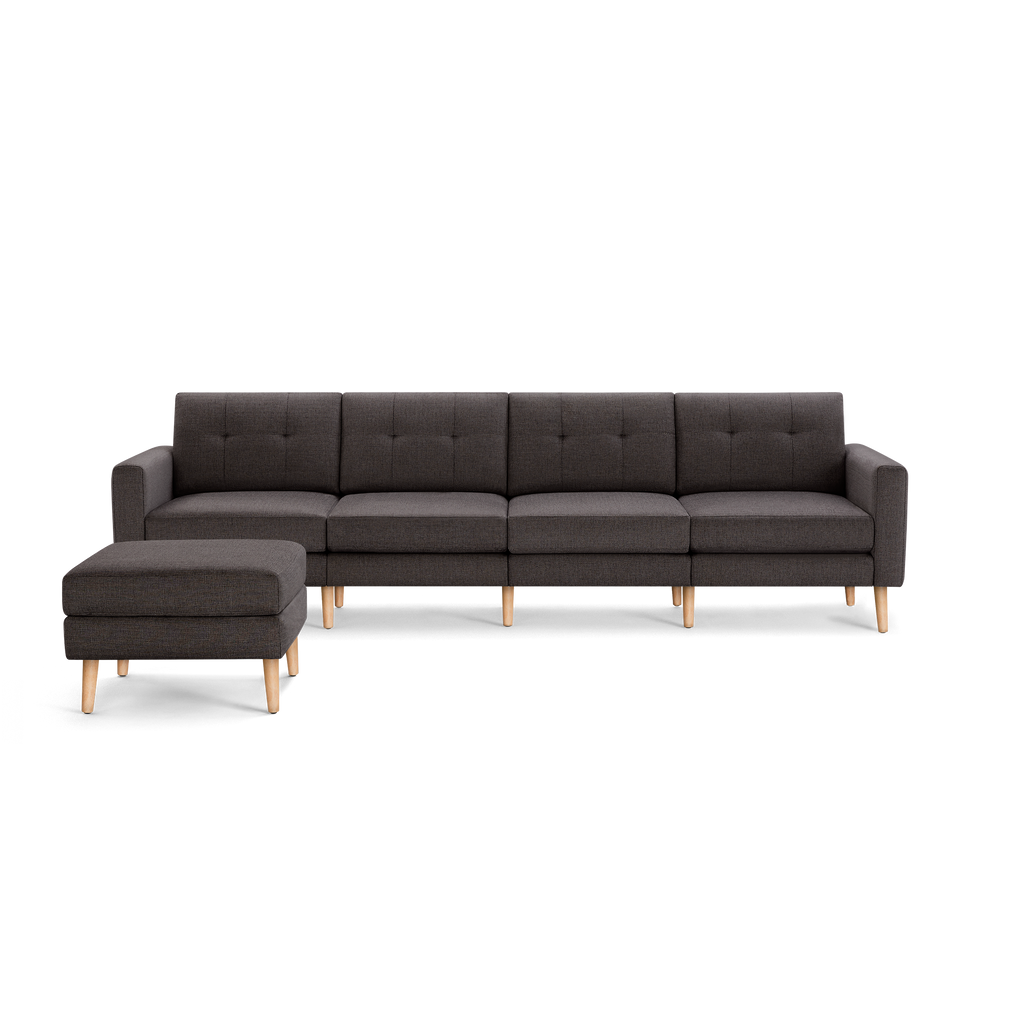 Dark gray modular sectional sofa with tufted back cushions and matching ottoman, supported by light wooden legs.