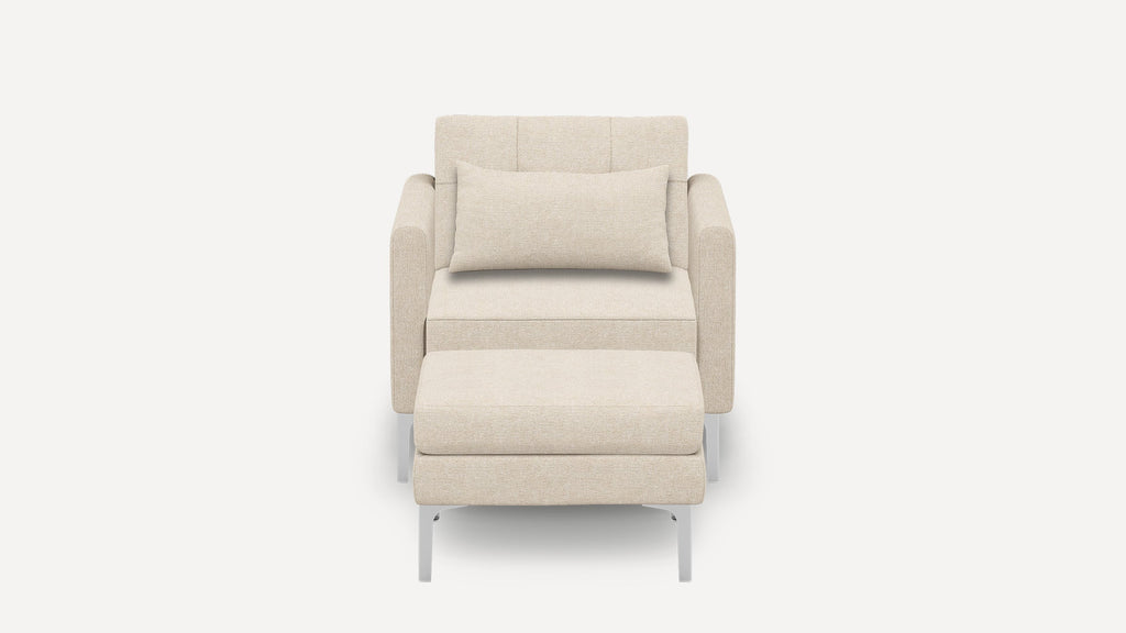 Front view of a modern beige upholstered armchair with a matching ottoman and a rectangular lumbar pillow.