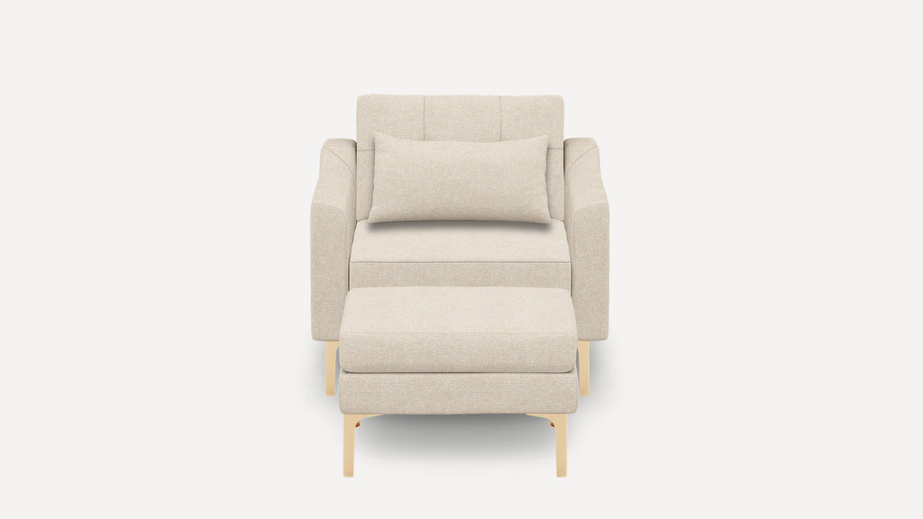 Modern beige fabric armchair with matching cushioned ottoman and rectangular lumbar pillow, supported by light wooden legs.