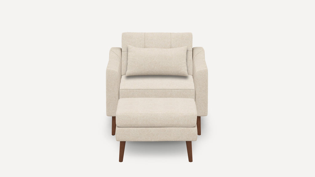 Beige upholstered armchair with matching rectangular cushion and ottoman, featuring wooden tapered legs on a white background.