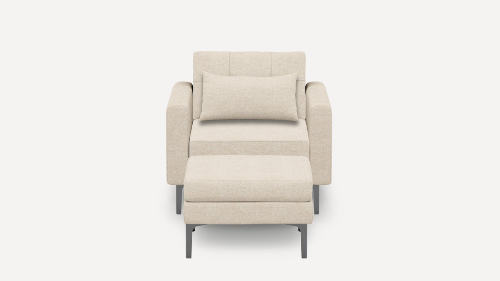 Modern beige armchair with matching rectangular cushion and ottoman, featuring sleek metal legs and soft fabric upholstery.
