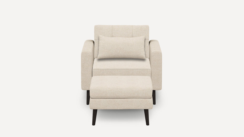 Beige fabric armchair with rectangular cushion and matching ottoman, supported by dark wooden tapered legs, pictured against a white background.