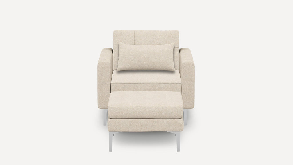 Front view of a beige upholstered armchair with a matching rectangular cushion and ottoman, featuring silver metal legs.