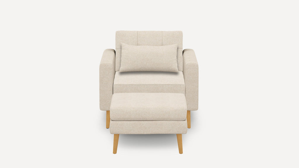 Front view of a beige upholstered armchair with matching rectangular lumbar pillow and ottoman, featuring light wooden tapered legs.