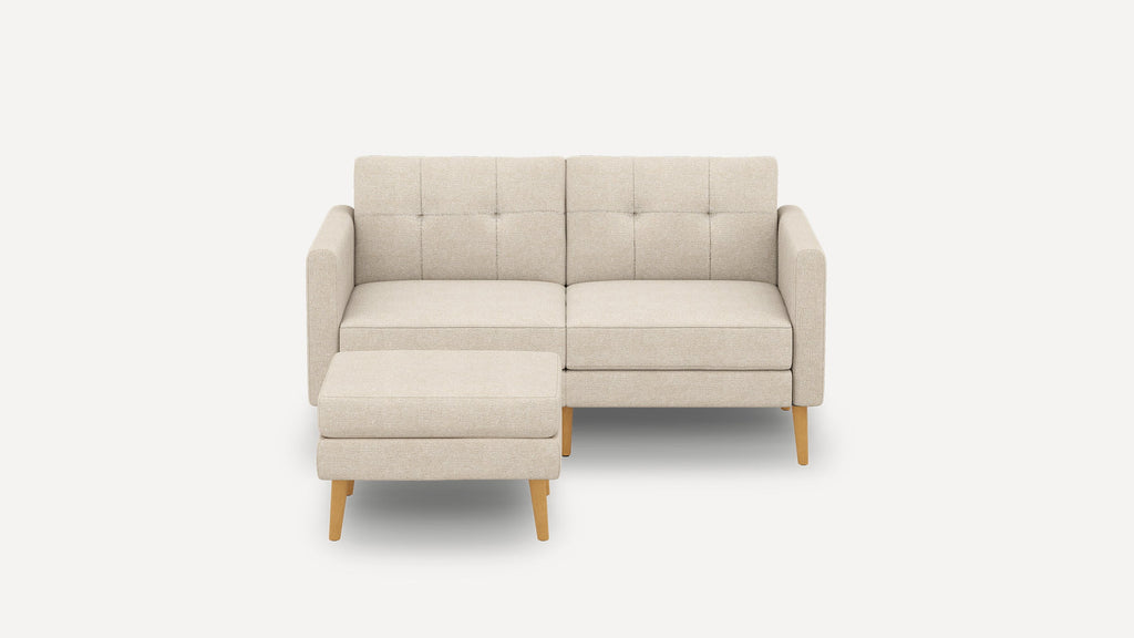 Beige modern two-seater sofa with tufted backrest and matching ottoman, featuring light wooden legs and clean-lined design.