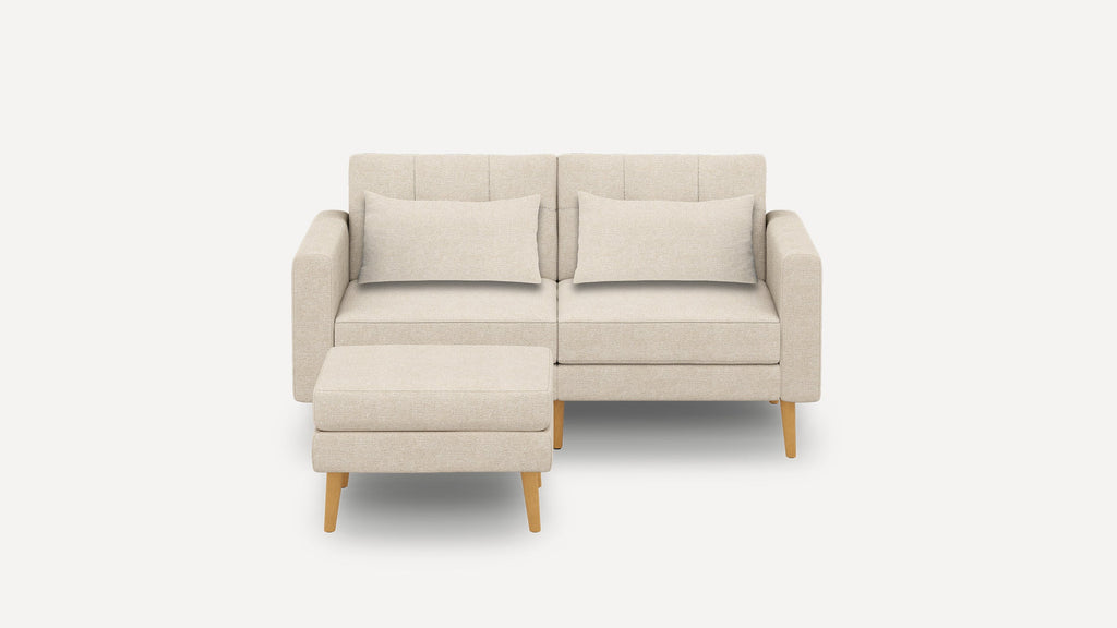 Beige modern loveseat sofa with two rectangular cushions and matching ottoman, supported by light wooden legs.