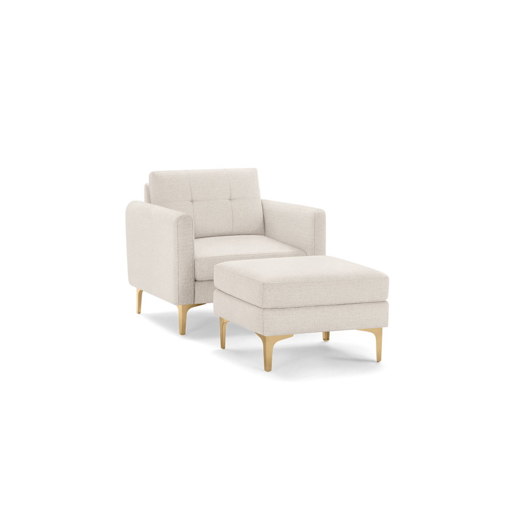 Beige upholstered armchair with matching ottoman, tufted backrest, and gold metal legs, showcasing modern minimalist design.