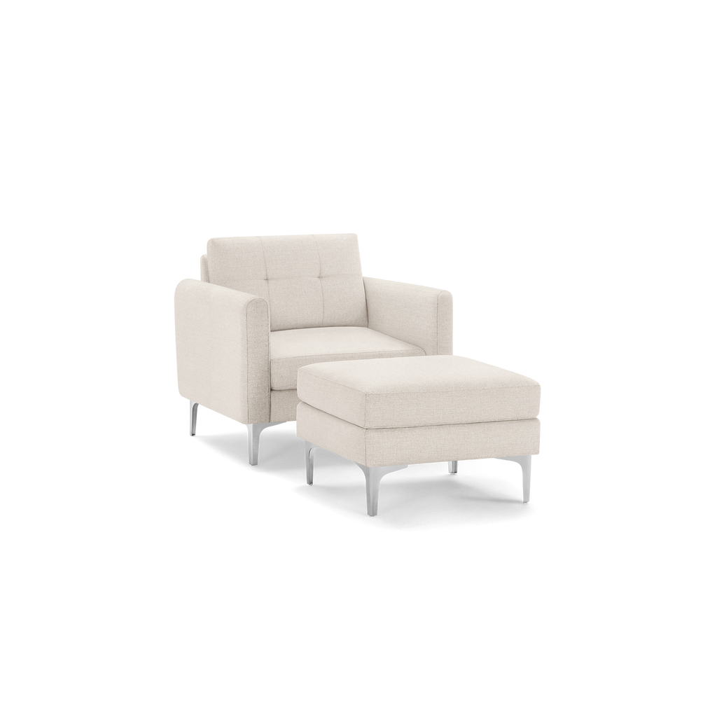 Modern beige fabric armchair with tufted backrest and matching cushioned ottoman, supported by sleek metal legs.