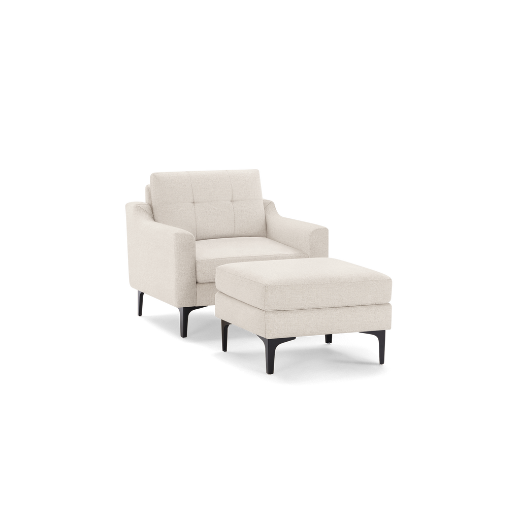 Beige fabric armchair with black metal legs, accompanied by a matching cushioned ottoman with similar leg design.
