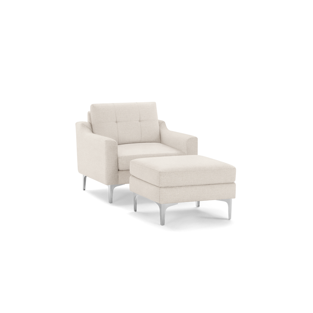 Beige upholstered armchair with tufted backrest and matching cushioned ottoman, both featuring slender silver metal legs.