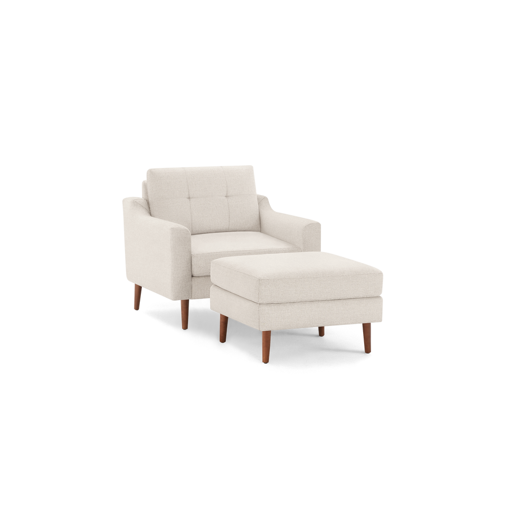 Beige upholstered armchair with tufted backrest and matching ottoman, both featuring wooden tapered legs.