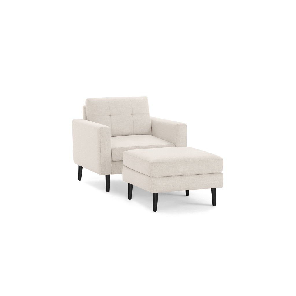 Beige upholstered armchair with tufted backrest and matching ottoman, supported by black tapered wooden legs.