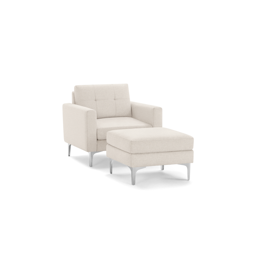 Cream-colored modern armchair with tufted backrest and matching cushioned ottoman, both featuring sleek metal legs.