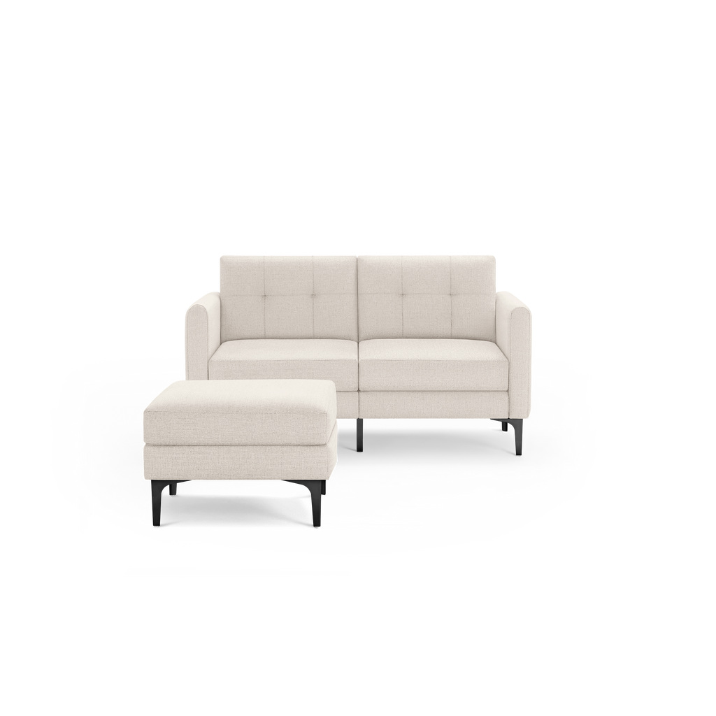 Beige fabric loveseat with black legs, featuring tufted back cushions and a matching ottoman in front.