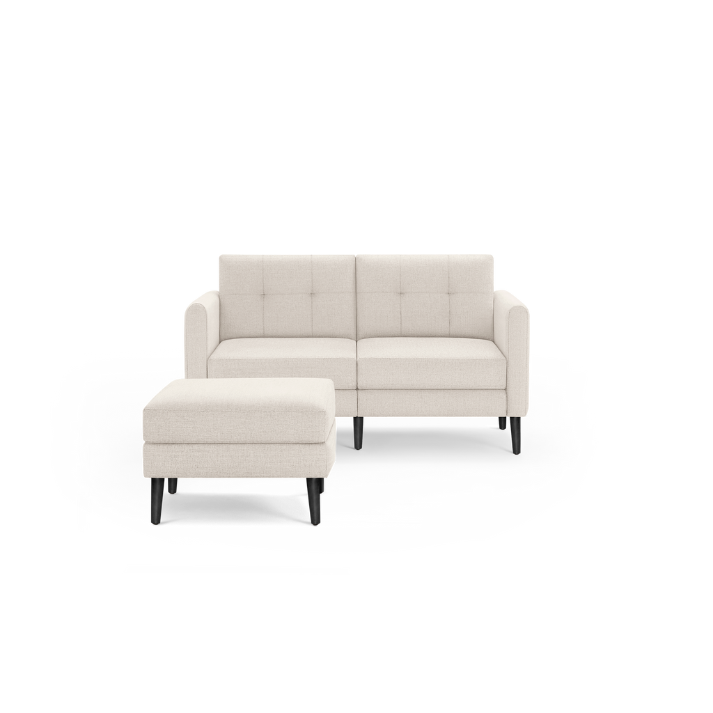 Beige fabric loveseat with tufted backrest, square armrests, and matching ottoman on black wooden legs.
