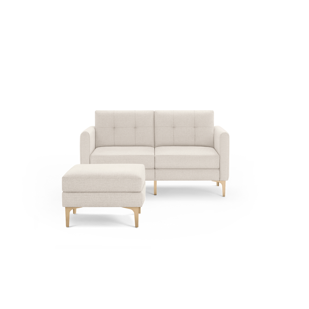 Beige upholstered two-seater sofa with matching ottoman, featuring tufted cushions and wooden legs in mid-century modern style.